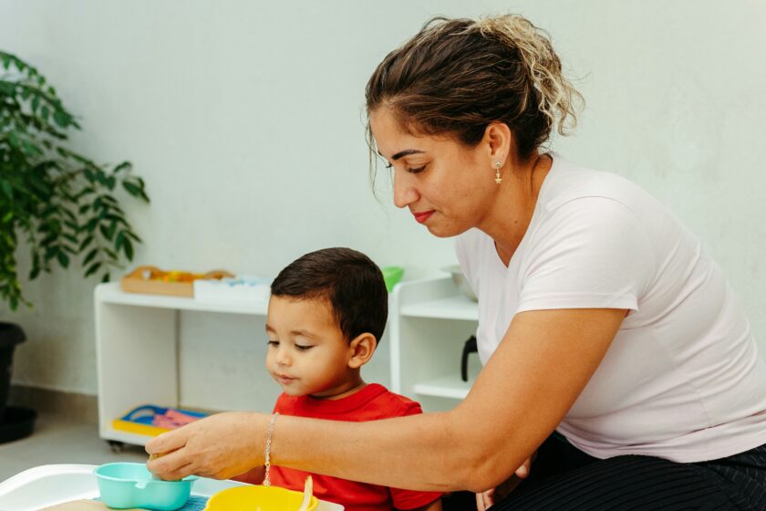 An educator sitting with child at meal time at their childcare centre.